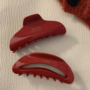 Pinces à cheveux en acétate rouge foncé avec lettrage doré sur fond texturé élégant