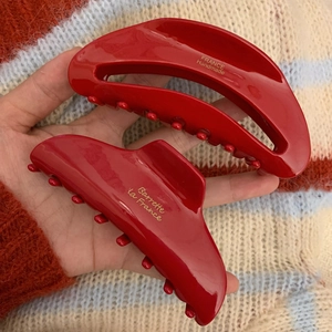 Détail des pinces à cheveux en acétate rouge avec logo doré et texte fait main