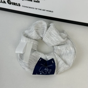 Dettaglio dell'elastico a righe grigie con etichetta di orso e decorazione a nastro