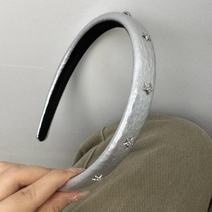 Detail of silver faux leather headband with metallic star studs and sparkling rhinestones