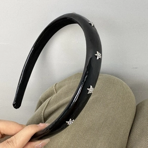 Detail of a black faux leather headband featuring silver star rhinestones and thick padding
