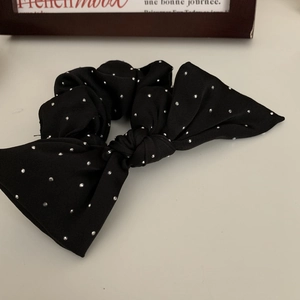 Detailed macro shot of a black bow scrunchie with shimmering silver rhinestones