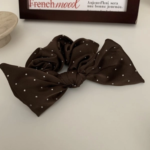 Detailed close-up of dark brown satin bow scrunchie with sparkling silver rhinestones