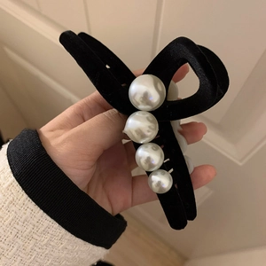 Close-up of black velvet hair claw clip with gradient white pearls in hand