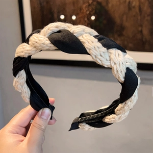Close-up of beige knitted rope and black silk ribbon braided headband with textured weave