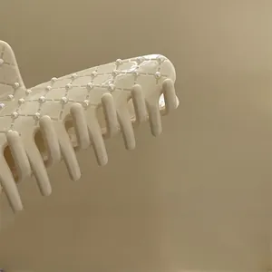 Gros plan sur la pince à cheveux beige avec motif en losanges et perles élégantes