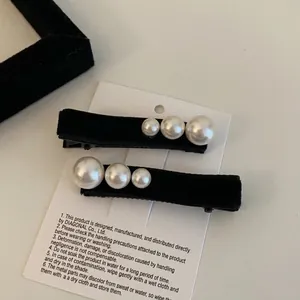 Detailed close-up of French velvet hair clips with elegant pearl beads on a white card