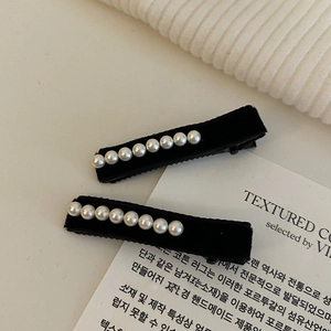 Detail of two black velvet hair clips with white faux pearls for elegant hair styling
