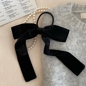 Elegant black velvet bow hair tie with long streamers on a stylish knit background