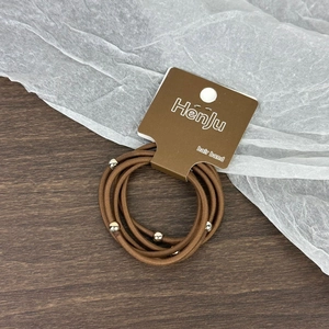 Détail d'élastiques marrons avec perles argentées sur carte de support, texture tissée