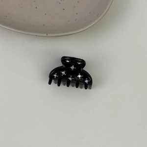 Dettaglio molletta per capelli in acetato nero con strass colorati e scritte in oro