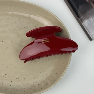 Close-up of a deep red acetic acid hair claw clip with golden handmade lettering