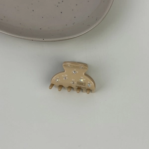 Dettaglio della molletta beige in acetato con strass scintillanti e scritta France Handmade