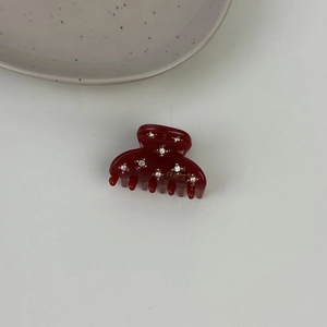 Dettaglio del fermaglio per capelli in acetato rosso vino con strass scintillanti incastonati