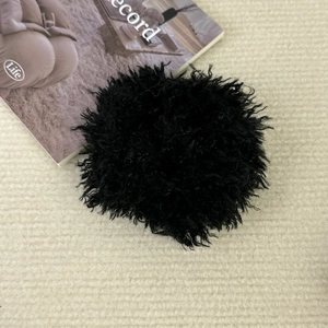 Gros plan sur chouchou en peluche noire avec texture douce en fausse fourrure bouclée sur tricot