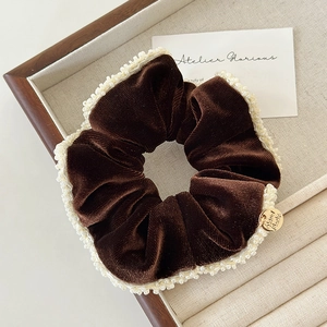 Detail of dark brown velvet scrunchie with white beads and a gold handmade pendant