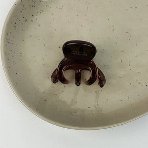 Détail de la pince à cheveux écaille avec logo doré France Handmade sur surface en acétate