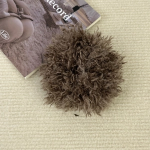 Vue détaillée d'un chouchou en peluche marron doux sur fond texturé de couleur beige
