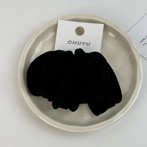 Detail of soft black velvet scrunchie with elastic band in a minimalist display setting