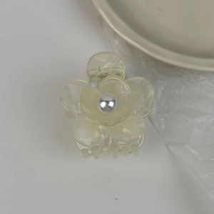 Détail d'une pince à cheveux fleur jaune translucide avec une perle argentée au centre