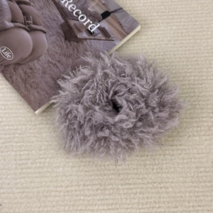 Détail d'un chouchou en peluche gris moelleux sur un fond en maille douce