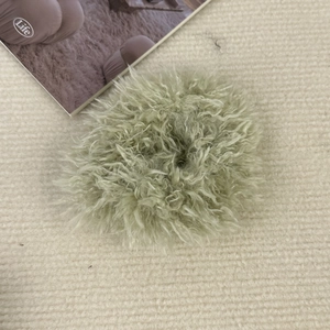 Vue détaillée d'un chouchou en peluche vert clair sur un fond de tissu beige texturé