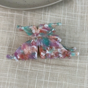Detailed macro view of large 3D butterfly hair claw with colorful marble texture resin