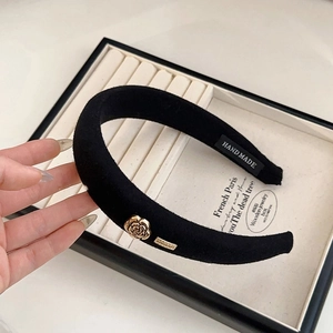 Detail of black velvet padded headband featuring a gold rose charm and handmade label