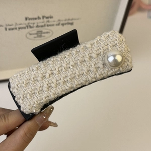 Close-up of elegant beige tweed shark hair claw clip with pearl accent for women