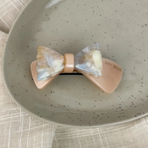 Detail of acetate double-layer bow hair clip with marbled texture and AMY BEAR engraving
