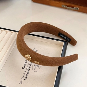 Detail of vintage brown sponge headband with a golden rose and handmade label