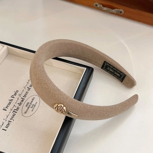 Detailed close-up of beige camellia sponge headband with gold rose and hand made label