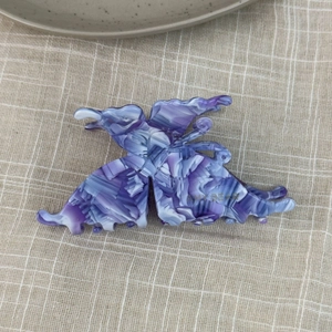 Detail view of purple marbled acetate butterfly hair claw clip on beige checkered fabric