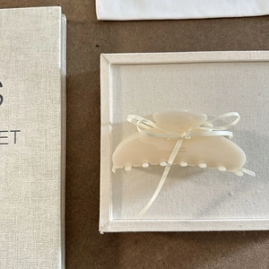 Dettaglio macro di una pinza per capelli in acetato crema con nastro su vassoio