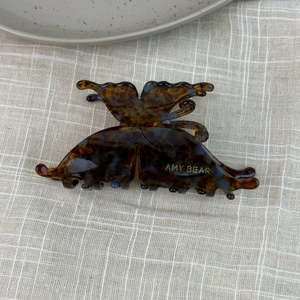 Detailed view of butterfly claw clip with tortoiseshell pattern on linen fabric