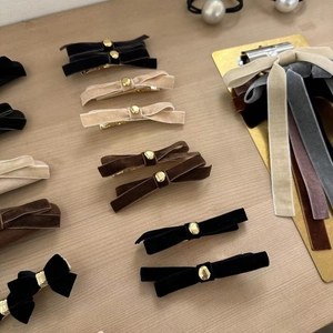 Close-up of velvet bow hair clips with gold bead accents in various vintage colors