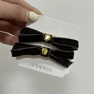 Detail of dark velvet bow hair clips with gold center piece on a white display card