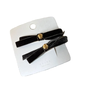 Pair of black velvet bow hair clips with gold metal buckles on a white card display