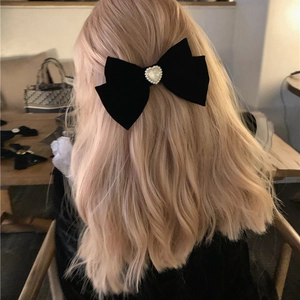 Elegant black velvet bow hair clip with heart pearl decoration on blonde wavy hair