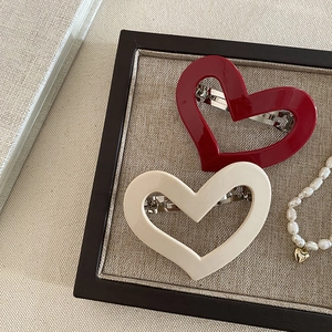 Red and cream hollow heart cellulose acetate hair clips in a decorative tray