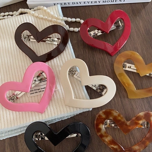 Colorful heart-shaped acetate hair clips collection on a wooden surface with pearls