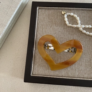 Detail of heart-shaped tortoiseshell hair clip on a tray with pearl necklace
