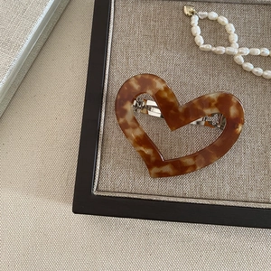 Detail of a brown tortoiseshell heart hair clip with a silver metal spring clasp