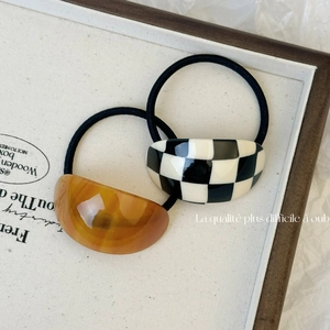 Minimalist acetate hair ties featuring checkered and amber patterns on a canvas tray