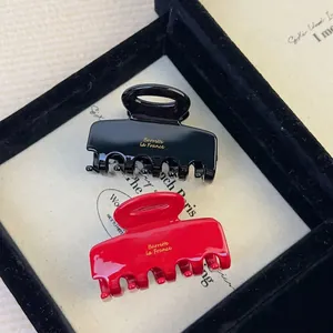 Elegant black and red acetate hair claws with gold France lettering in a jewelry box