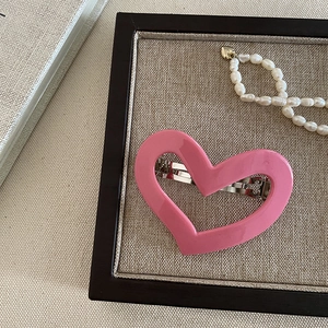 Detail of pink hollow heart-shaped hair claw with silver metal spring clip and smooth finish