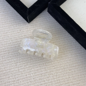 Detail showing the pearlescent white acetate finish and golden Barrette la France logo