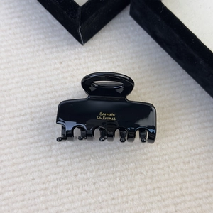 Close-up of black acetate hair claw clip with golden Barrette La France lettering