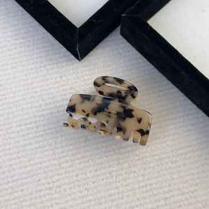 Detail of tortoise shell hair claw clip with gold France lettering on knit background