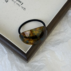 Detail showing the tortoiseshell pattern resin arc on a minimalist black hair tie